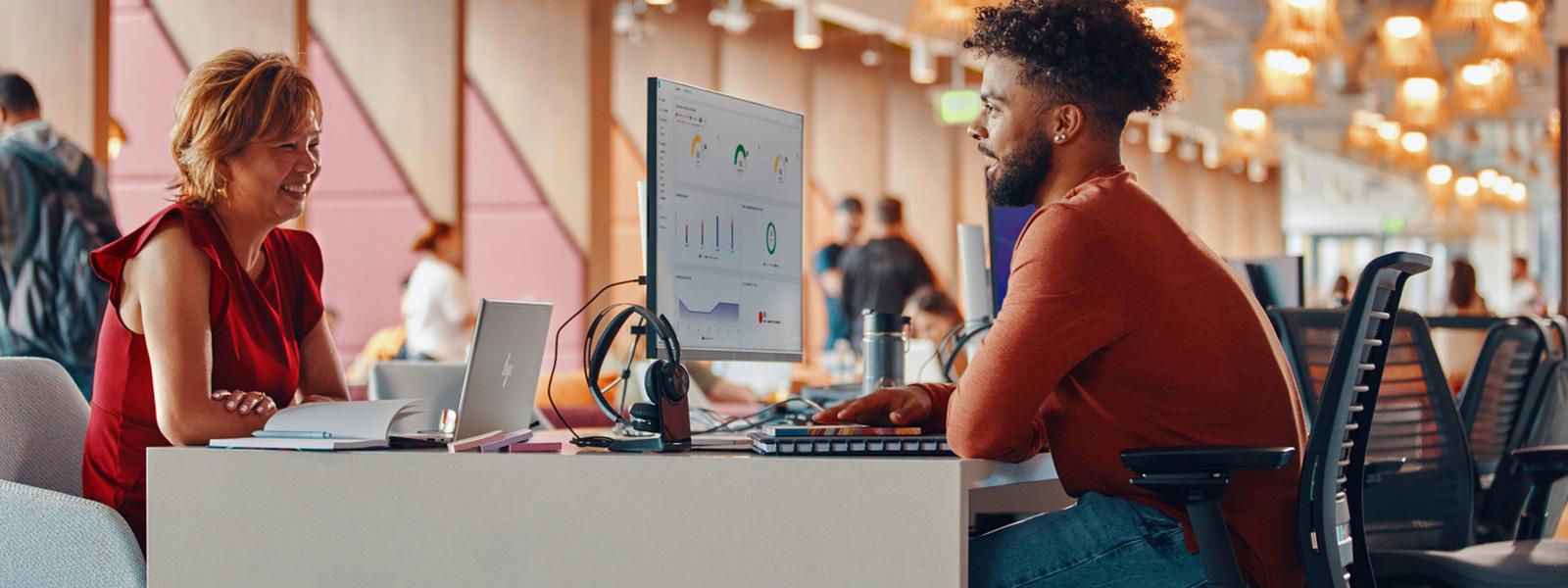 Two people sitting across from each other on a two sided digital workspace