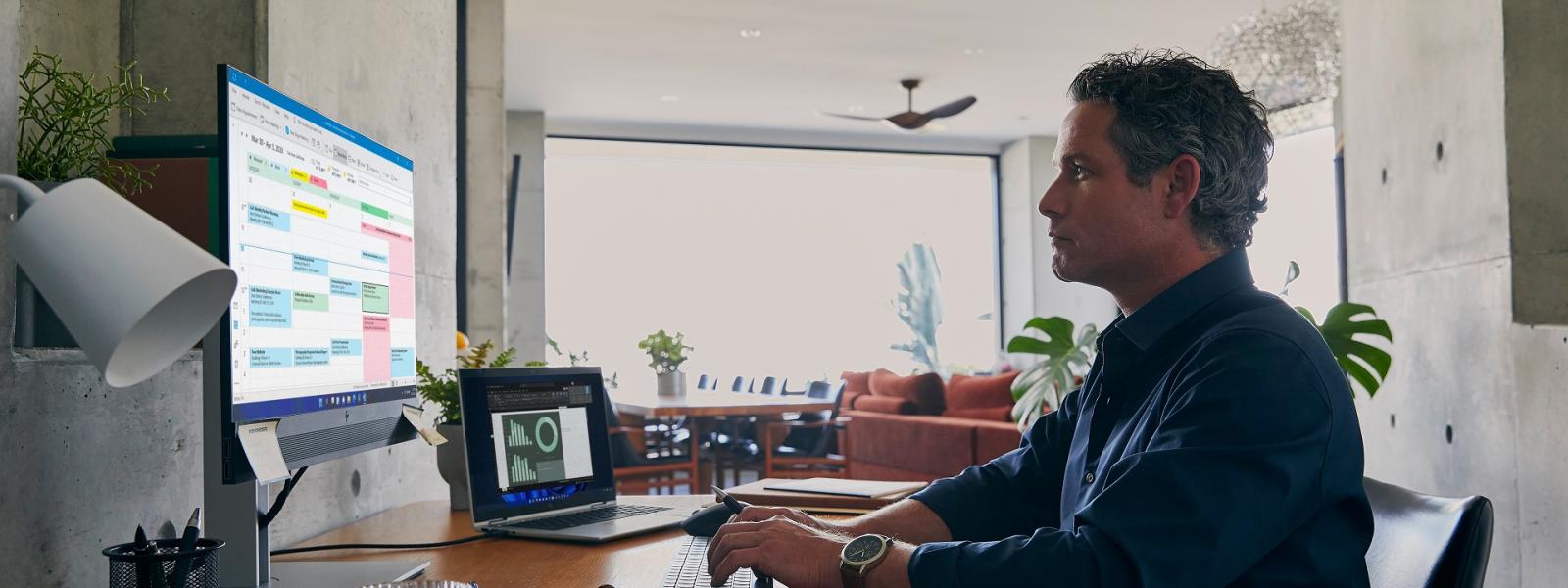 Man sitting at a desk typing on one screen