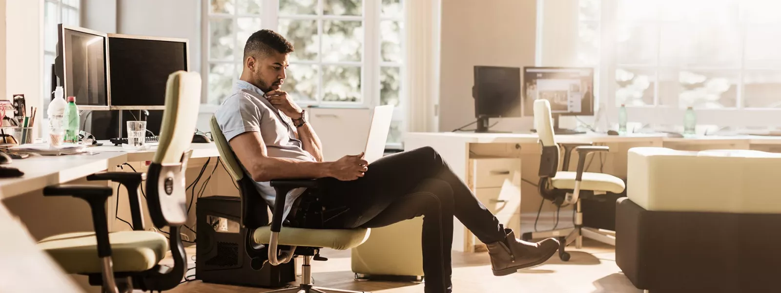 Man sitting in chair in home office with laptop on lap