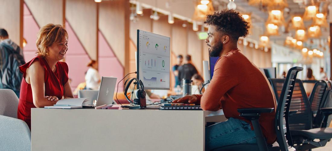 Two people sitting across from each other on a two sided digital workspace