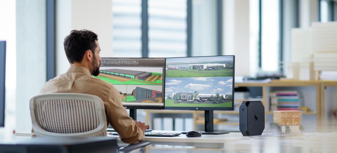 Man at desk working on two-screen computer