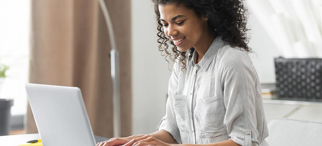 Woman at desk on laptop computer with a cup of coffee