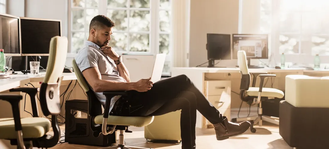 Man sitting in chair in home office with laptop on lap